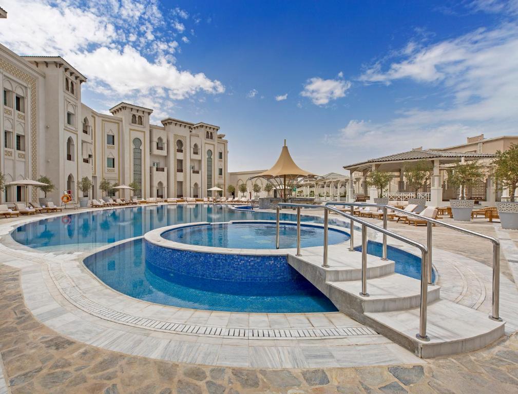 a swimming pool at a resort with buildings at Ezdan Palace Hotel in Doha