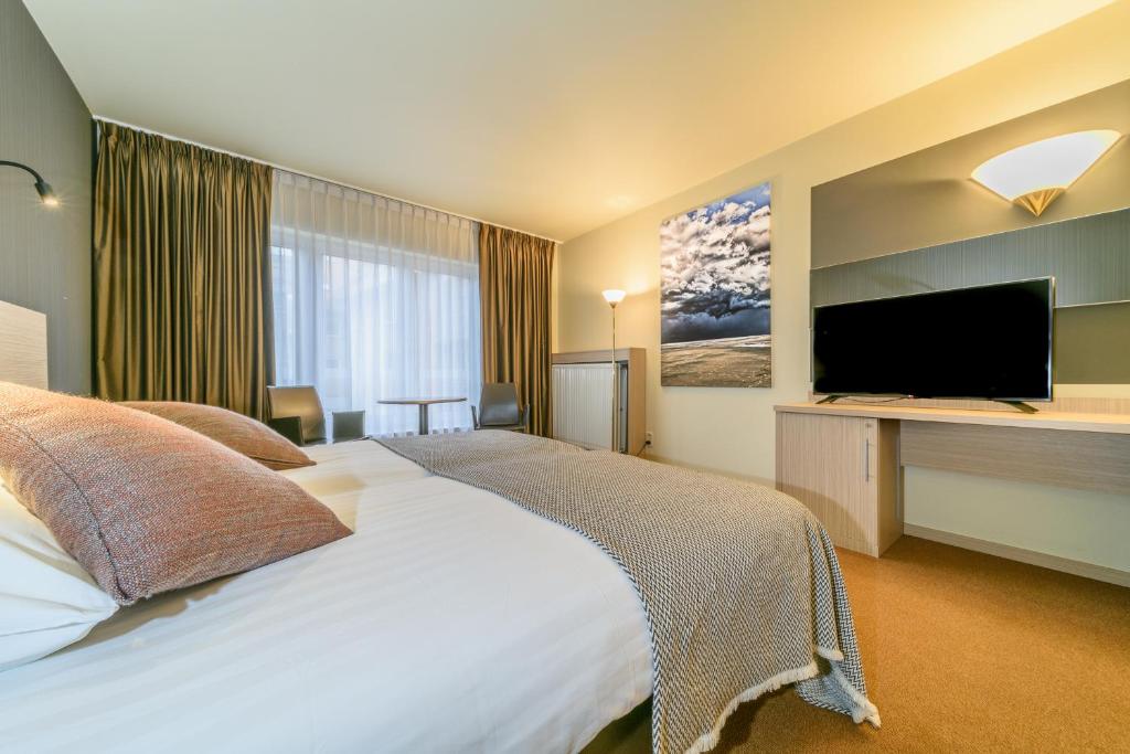 ein Hotelzimmer mit einem Bett und einem Flachbild-TV in der Unterkunft Cosmopolite Hotel Nieuwpoort-Bad in Nieuwpoort