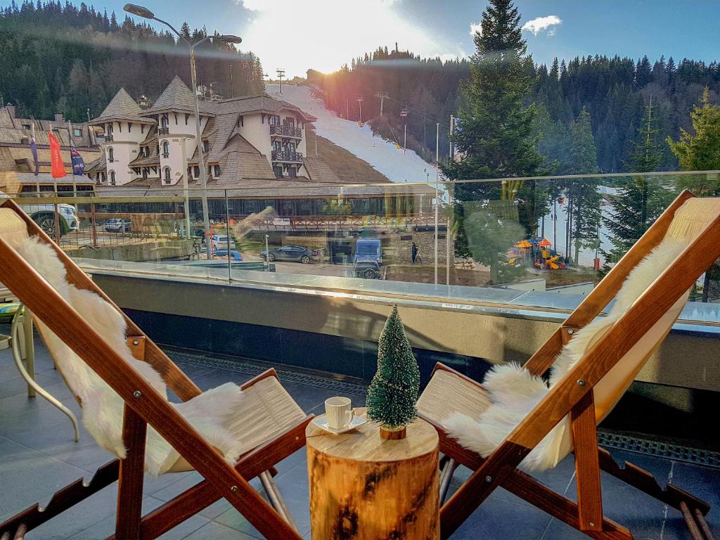 a balcony with two chairs and a table with a christmas tree at Olimpijska kuća - A103 in Jahorina