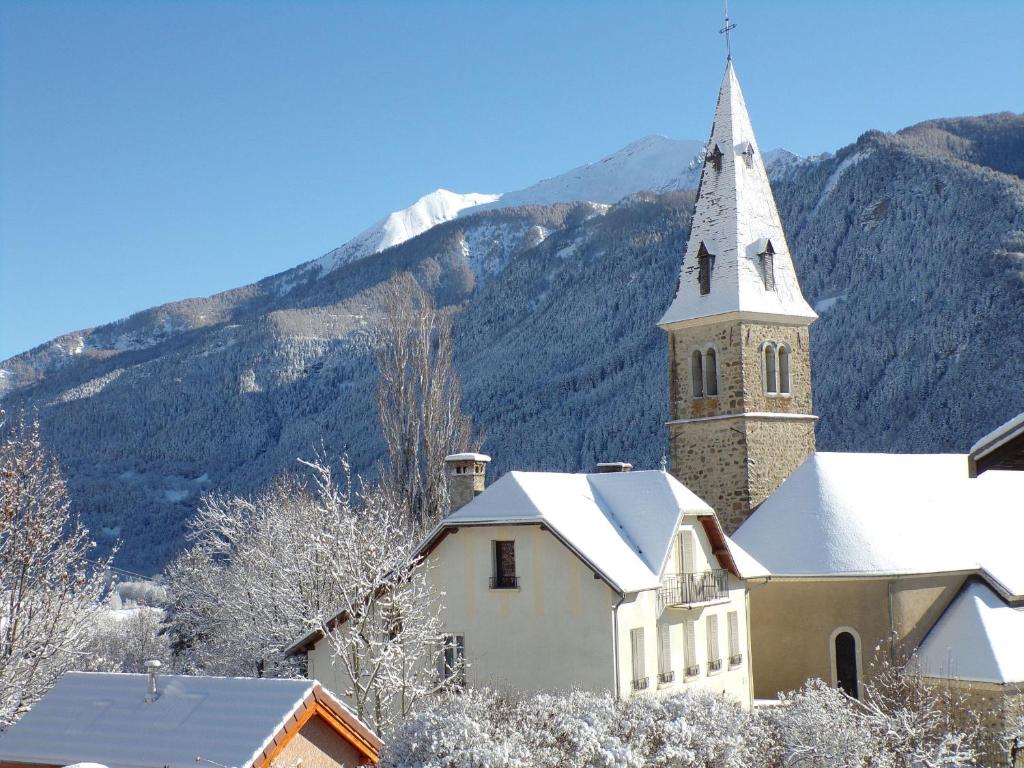 una iglesia con campanario y techo cubierto de nieve en LES PRIMEVERES en Saint-Jean-Saint-Nicolas