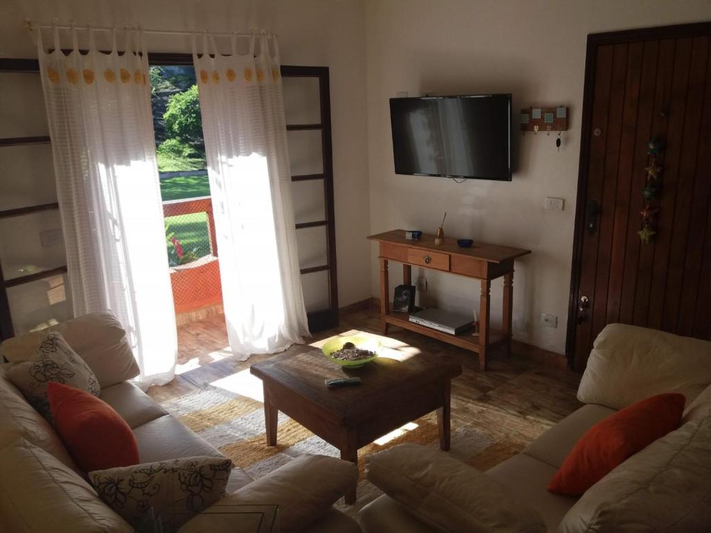 uma sala de estar com um sofá e uma televisão em Chalé em Ilhabela - Praia de Itaguassu em Ilhabela