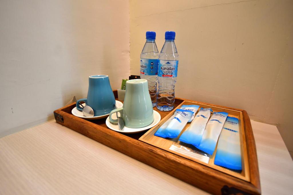 a wooden tray with cups and bottles of water at Taitung Venice B&amp;B in Taitung City