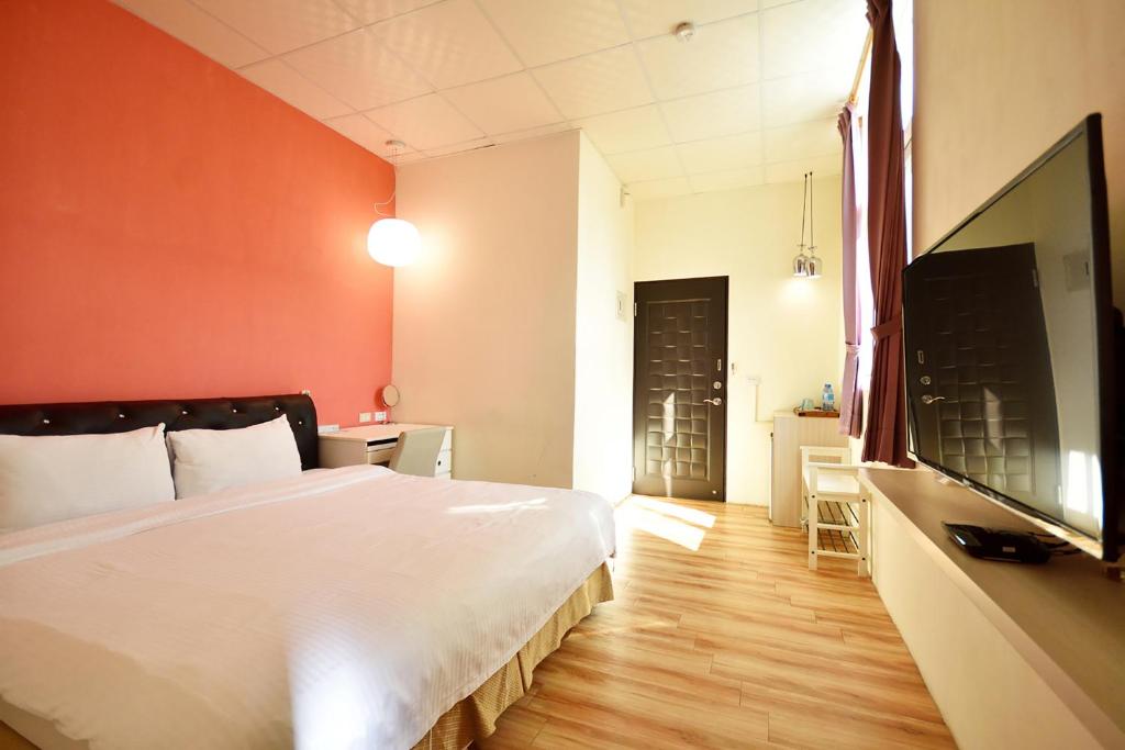 a bedroom with a large white bed and orange walls at Taitung Venice B&amp;B in Taitung City