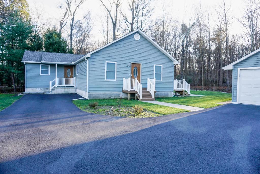 a blue house with a driveway at Cabin by the Creek with private creek access in Tannersville