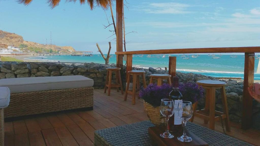 un patio con una mesa con copas de vino y vistas al océano en PUERTO "TE", en Máncora