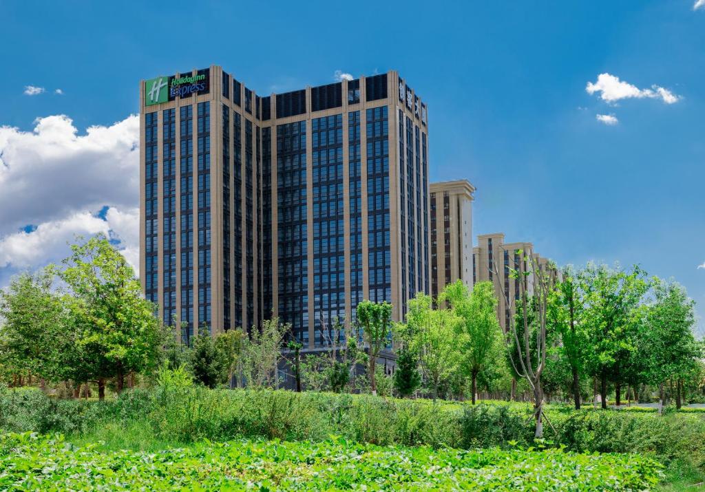 乌鲁木齐Holiday Inn Express Urumqi Station by IHG的前面有树木的高楼