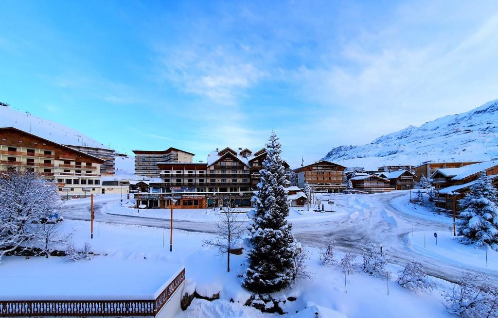 un complexe dans la neige avec un arbre de Noël dans l'établissement Hotel Les Bruyères, à L'Alpe-d'Huez