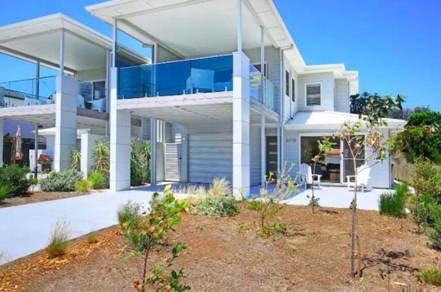 une grande maison blanche avec un balcon dans une cour dans l'établissement Ayada Villa - Pet Friendly - 1 Min to Beach, à Culburra Beach