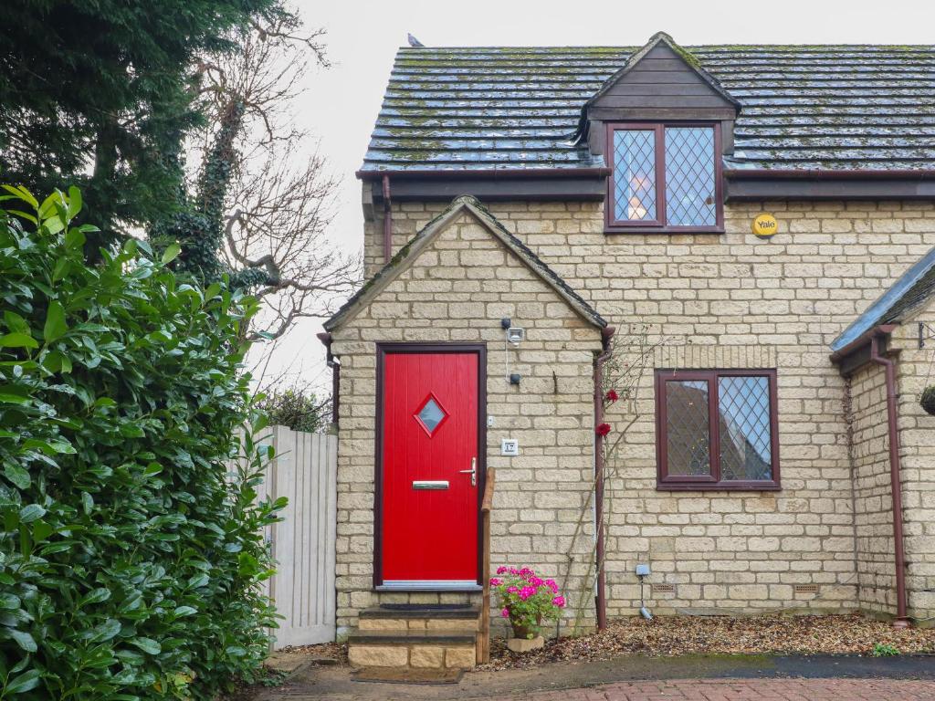 a red door on a brick house with a fence at The Seventeen in Bourton on the Water
