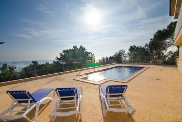 drie stoelen en een zwembad in de tuin bij Villa Breeze in Lloret de Mar
