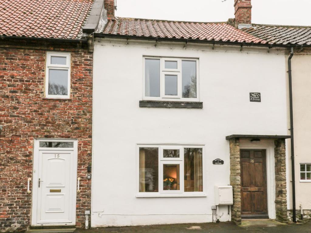 a white house with a door and windows at Barnaby Cottage in Yarm