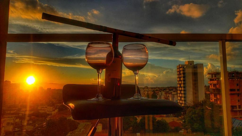 VIKINGS- Alto Padrão, Apto Rústico com conforto,Wifi e vista incrivel máx 4 في ساو كارلوس: كأسين من النبيذ يجلسون على طاولة أمام النافذة