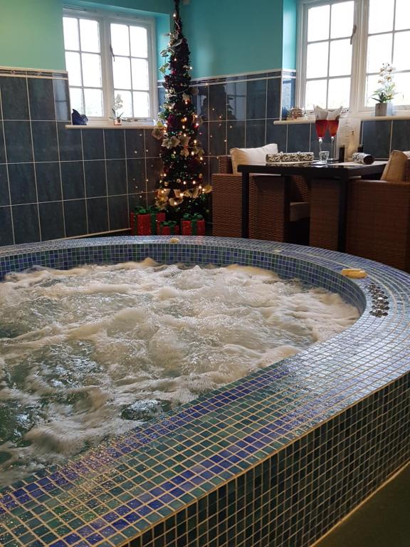 a jacuzzi tub with a christmas tree in a room at Igguldene Retreat with Jacuzzi in Deal