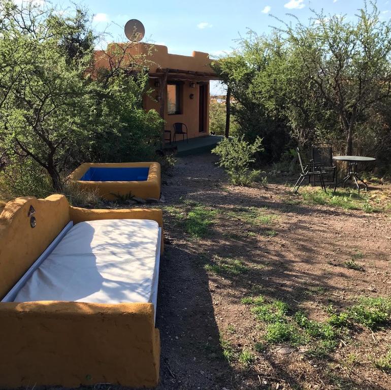 une cour avec 2 lits en face d'une maison dans l'établissement Cabañas Taos Pueblo, à Capilla del Monte