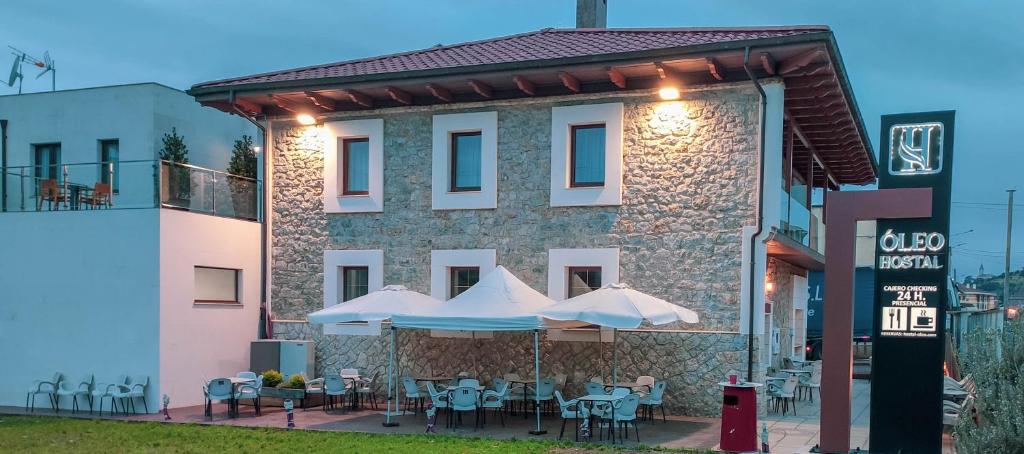 a building with tables and umbrellas in front of it at Hostal Óleo Auto Check-in in Santander