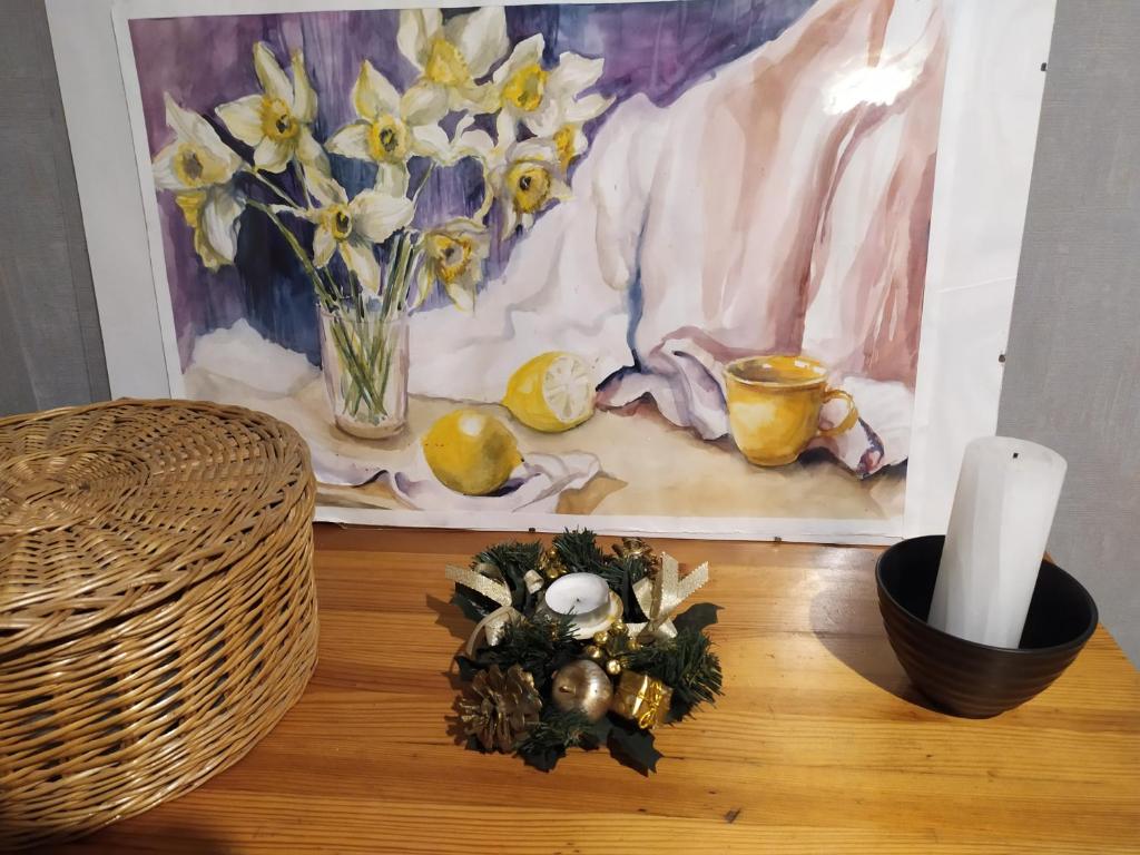 uma mesa com uma vela e flores e uma pintura em Апартаменти Світлий Ранок та Затишний Вечір em Rivne
