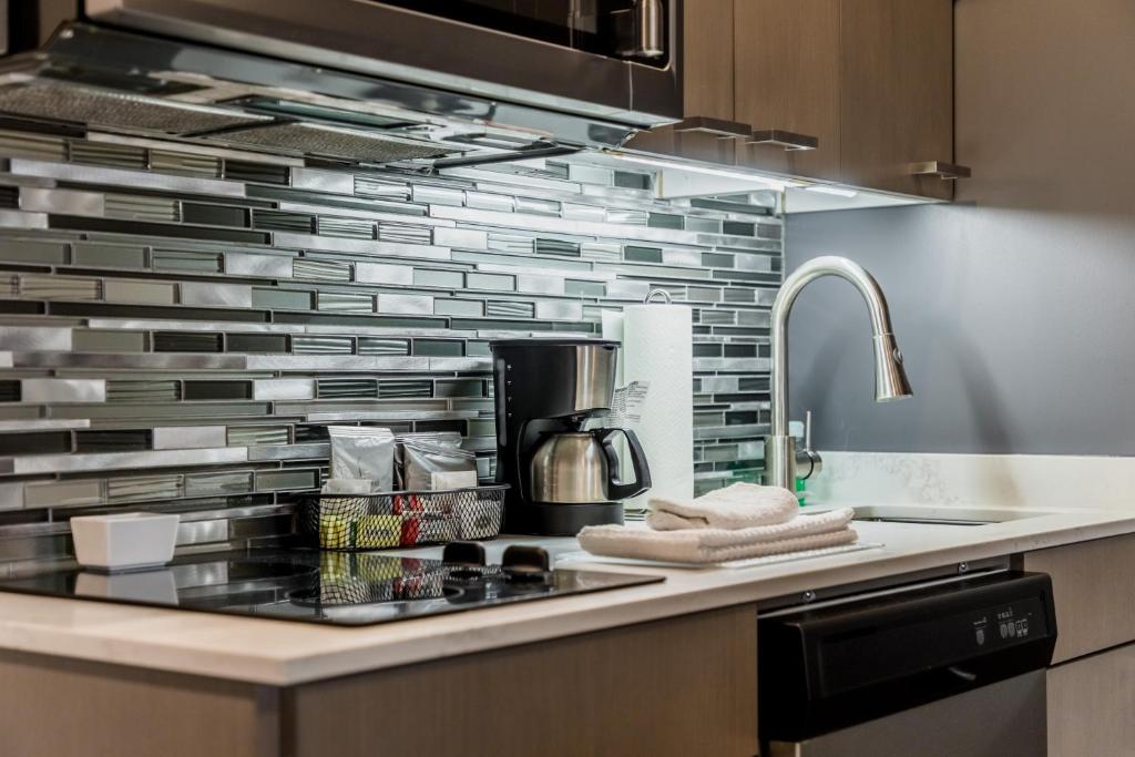 a kitchen with a stove top oven next to a sink at Hyatt House Winnipeg South Outlet Collection in Winnipeg