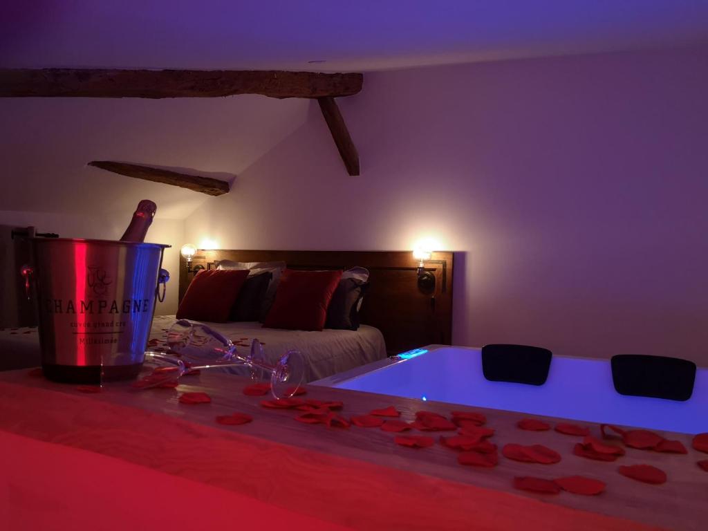 Pont-de-VeyleにあるEscapade Veyloise-Nuit romantique-Spa-Champagneのベッド1台、バラの入ったバスタブが備わる客室です。