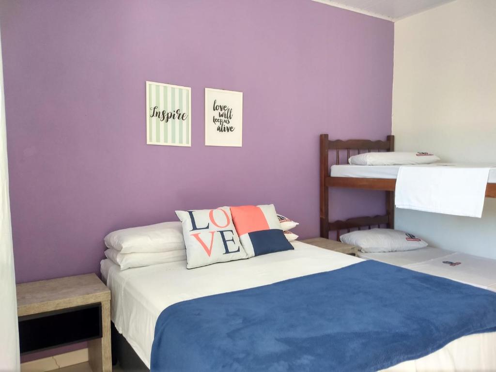 a bedroom with two beds and a purple wall at Pousada No Farol in Tramandaí