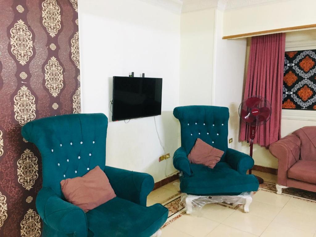 a living room with two chairs and a tv at Maadi Ring Road Sweet Apartment in Cairo