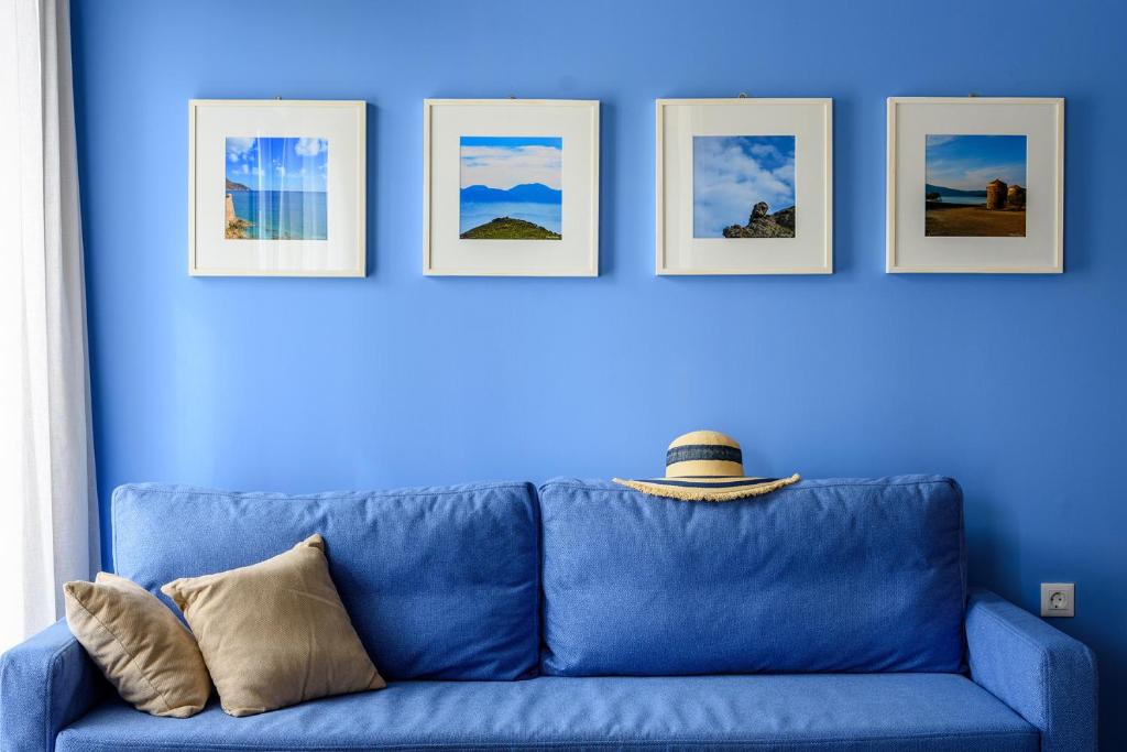 um sofá azul contra uma parede azul com quatro fotografias em Elounda Colour Apartments em Elounda