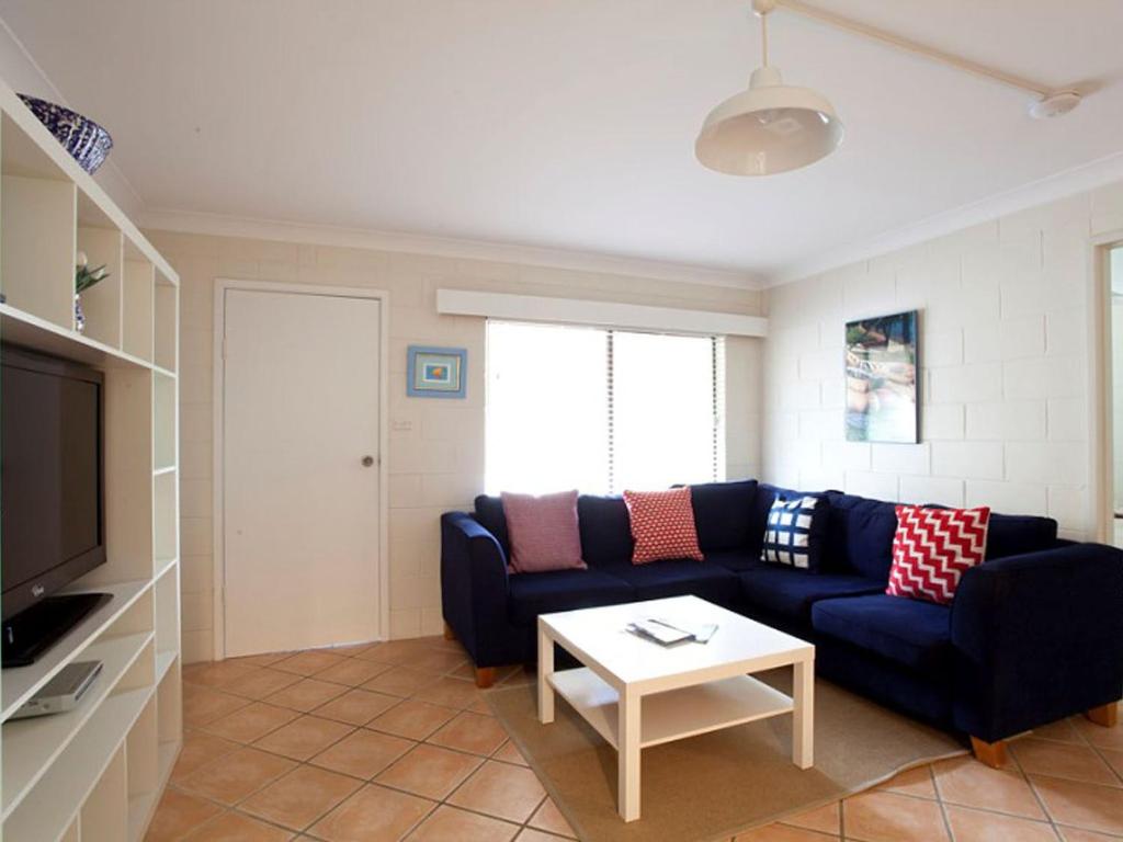 een woonkamer met een blauwe bank en een tafel bij Blueys Beach Villa Manyana 24 in Blueys Beach