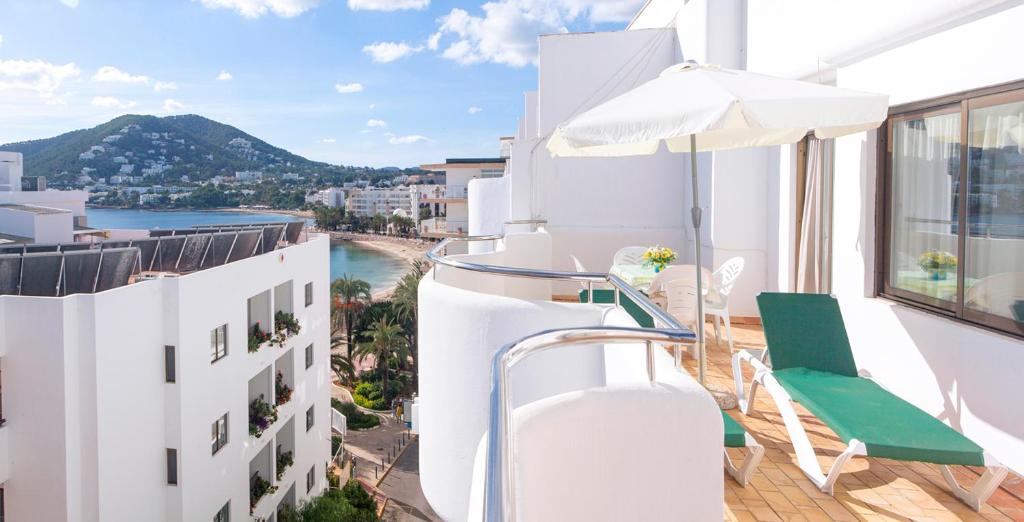balkon ze stołem, krzesłami i parasolem w obiekcie Apartamentos Bon Lloc w mieście Santa Eularia des Riu