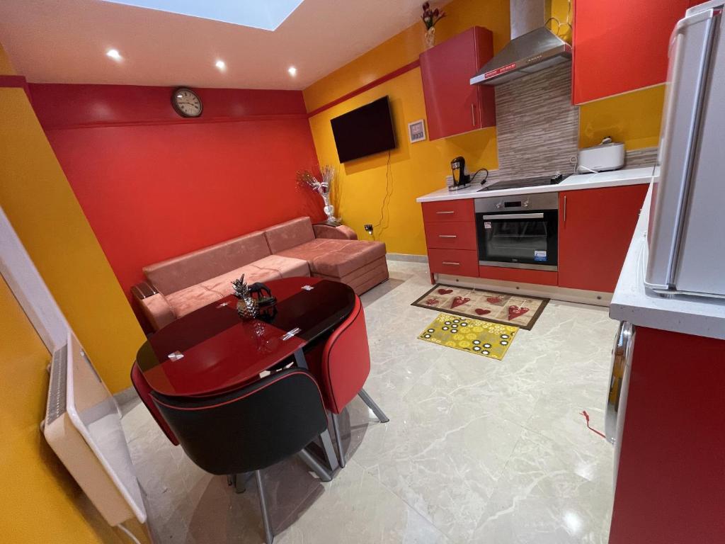 a kitchen with red and yellow walls and a couch at Modern Garden House in Harrow