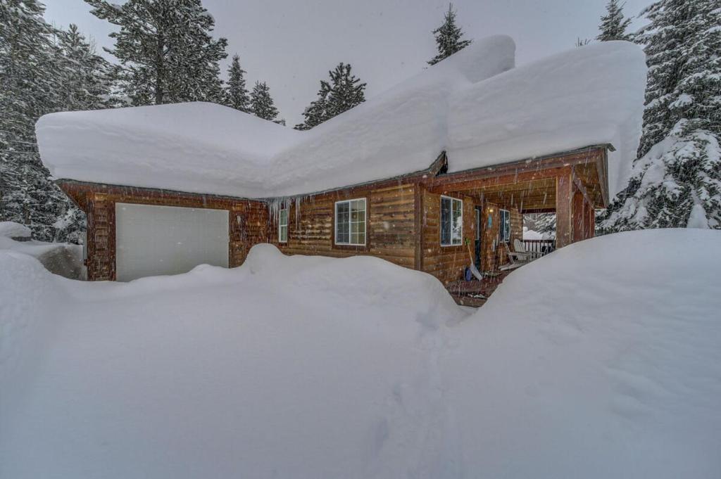 una casa ricoperta di neve con un mucchio di neve di Hubbard Cabin by Casago McCall - Donerightmanagement a McCall