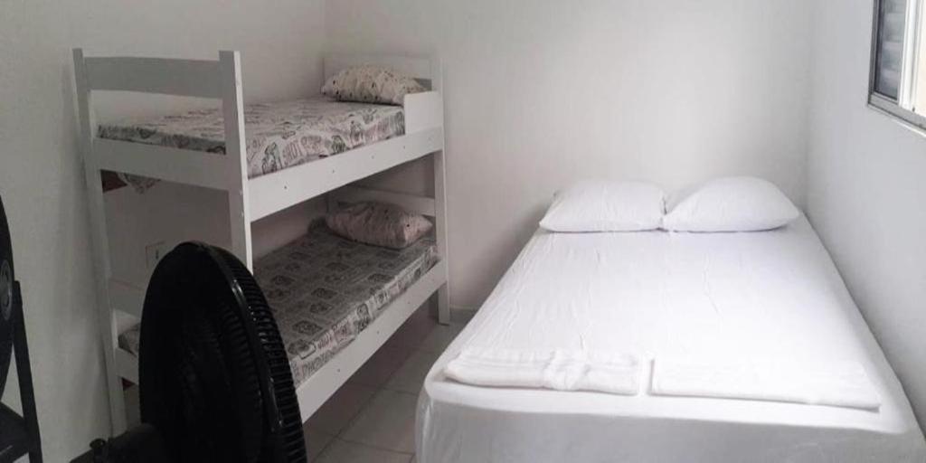 um pequeno quarto com 2 beliches e uma cadeira em Residencial Alemão no Guarujá