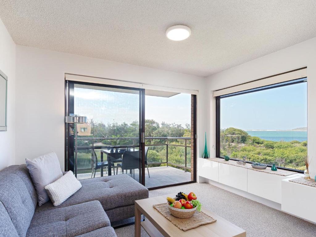 - un salon avec un canapé et une grande fenêtre dans l'établissement Intrepid 10 water views over Shoal Bay Beach, à Shoal Bay