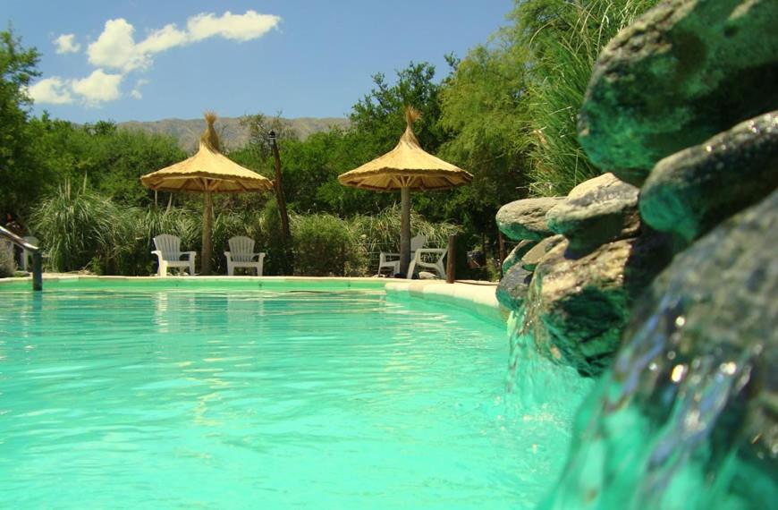 einen Pool mit 2 Sonnenschirmen und Stühlen sowie einem Pool in der Unterkunft Posada de campo Maia in Merlo