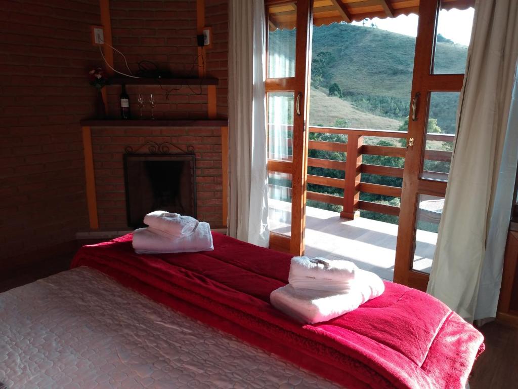 a bedroom with a bed and a fireplace with towels on it at Pousada Chales Joao de Barro in Visconde De Maua