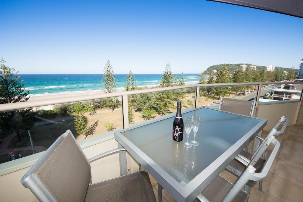 a person sitting at a table with a bottle of wine at Wyuna Beachfront Holiday Apartments in Gold Coast