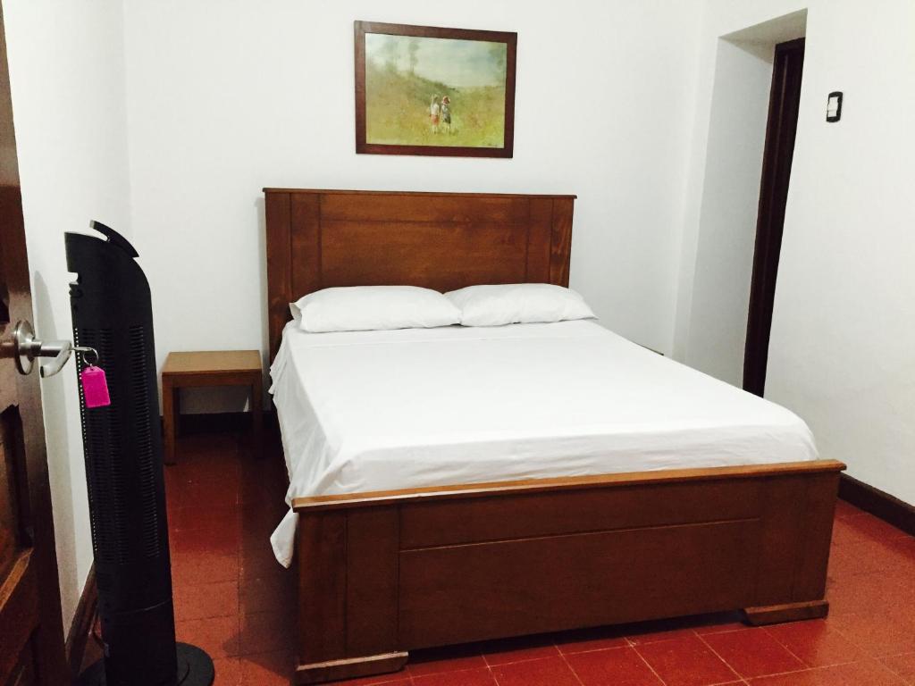 a bedroom with a bed with a wooden headboard at Casa Helga a dos cuadras de la Basílica, casa entera con jardín amplio, 6 habitaciones, 5 baños, cocina, comedor y sala de TV in Buga