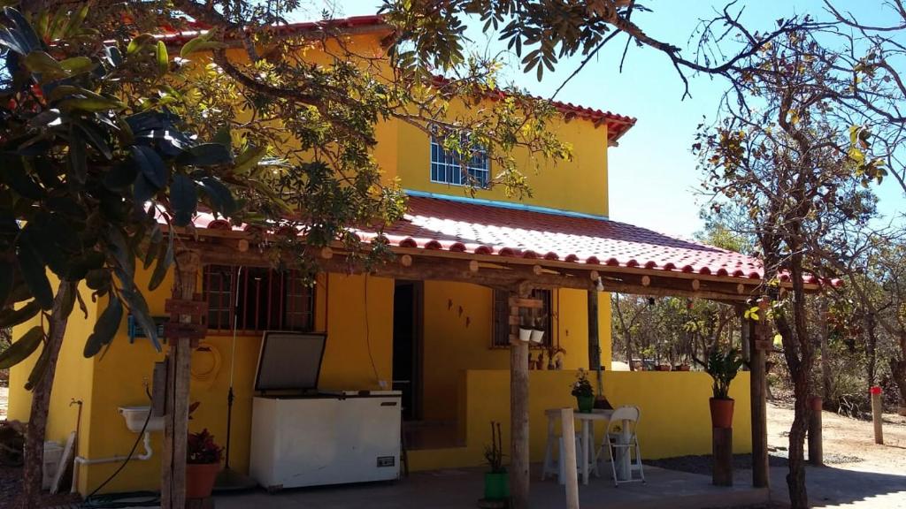 uma casa amarela com um alpendre e uma cozinha em Recanto da Aldeia - Lago dos Sonhos em Três Marias