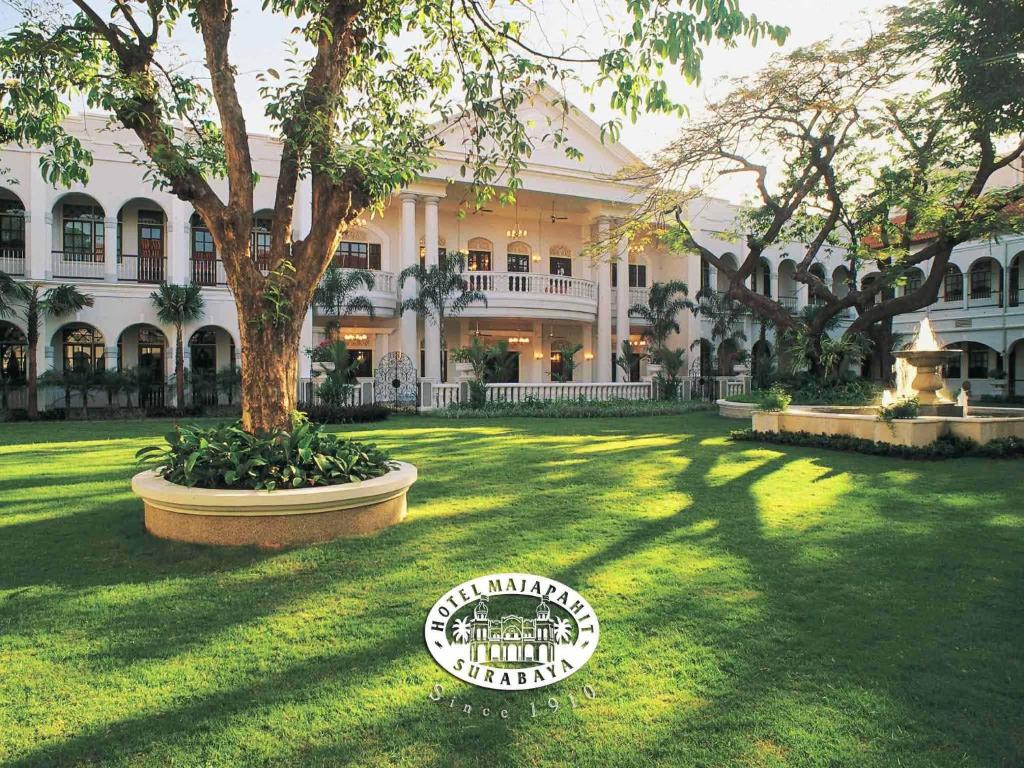 a large building with a tree in the yard at Hotel Majapahit Surabaya MGallery in Surabaya