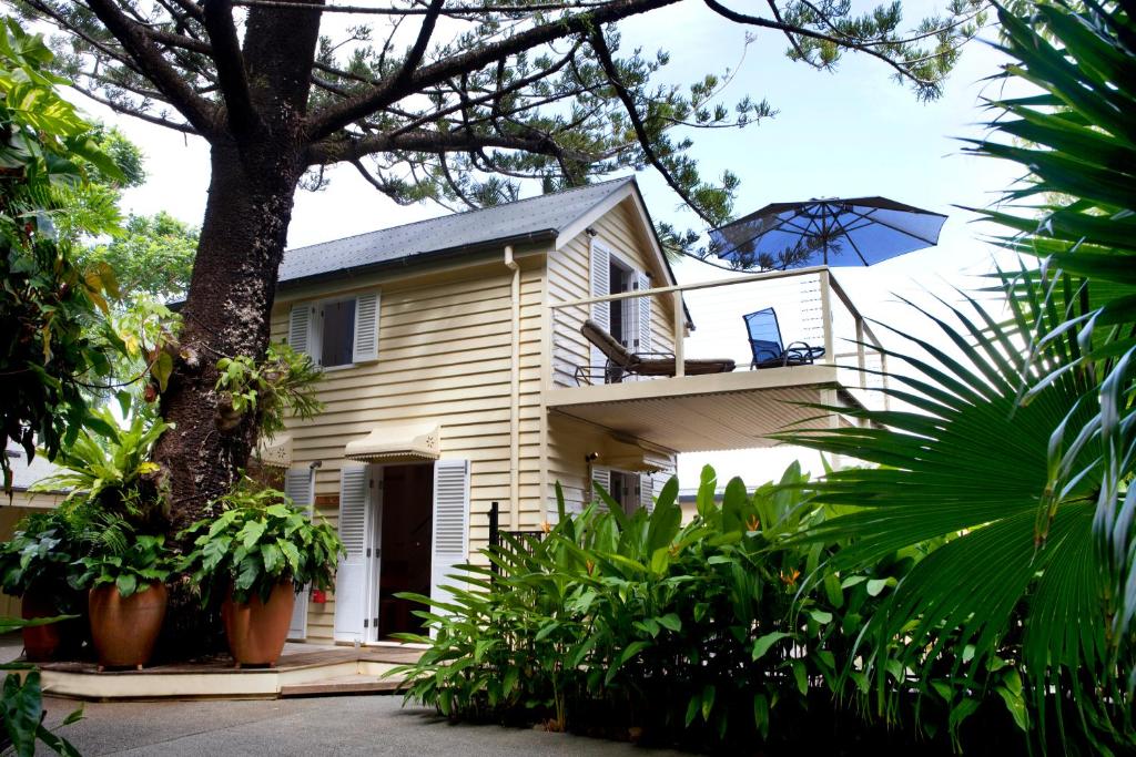 ein Haus mit einem Balkon mit einem blauen Regenschirm in der Unterkunft Port Douglas Cottage & Lodge in Port Douglas