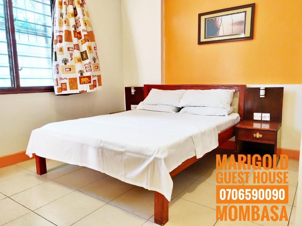 ein Schlafzimmer mit einem Bett in einem Zimmer mit einem Fenster in der Unterkunft Marigold Guest House in Mombasa