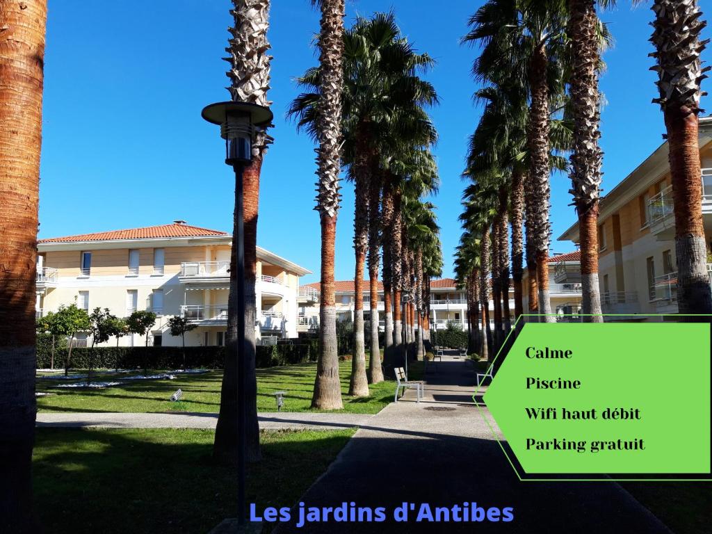 un panneau sur une rue avec des palmiers et un bâtiment dans l'établissement Les jardins d'Antibes, à Antibes