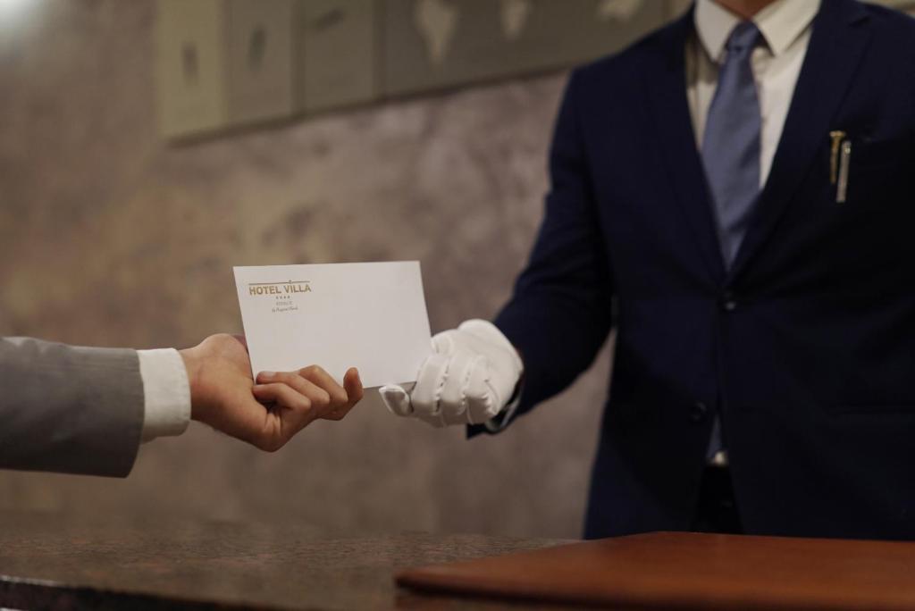 Un hombre con traje está estrechando la mano de otro hombre en Hotel Villa, en Bisceglie