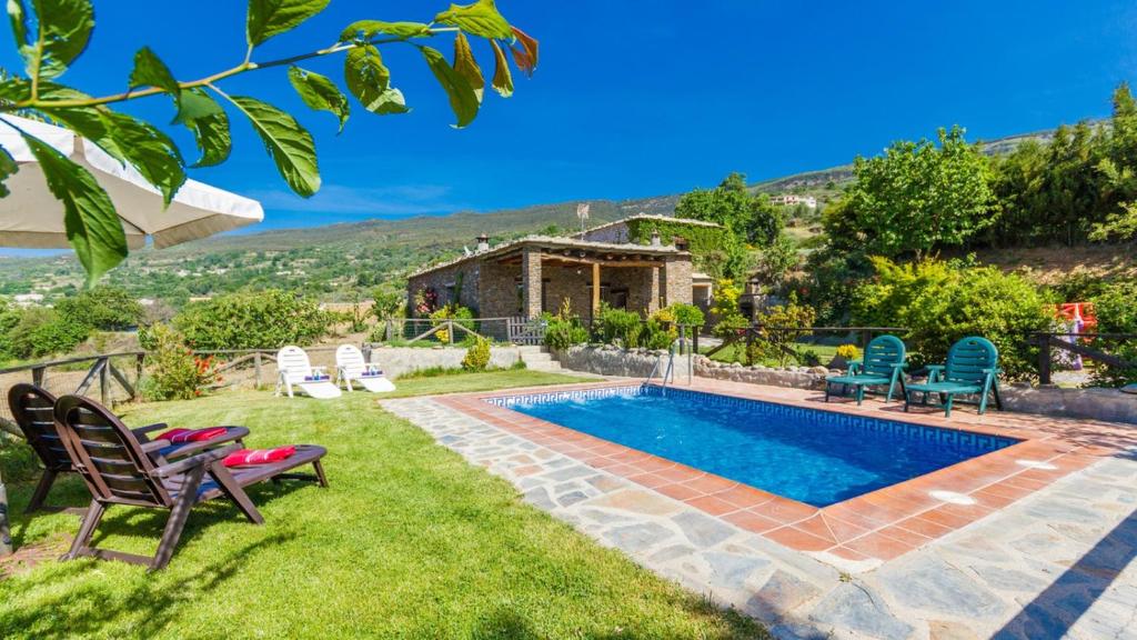 a backyard with a pool and chairs and a house at Cortijo Noguera La Taha - Pitres by Ruralidays in Granada