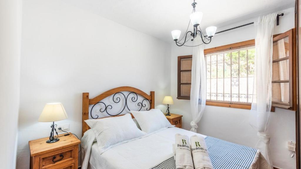 een slaapkamer met een bed met 2 lampen en een raam bij Villa Pinto Torrox by Ruralidays in Torrox