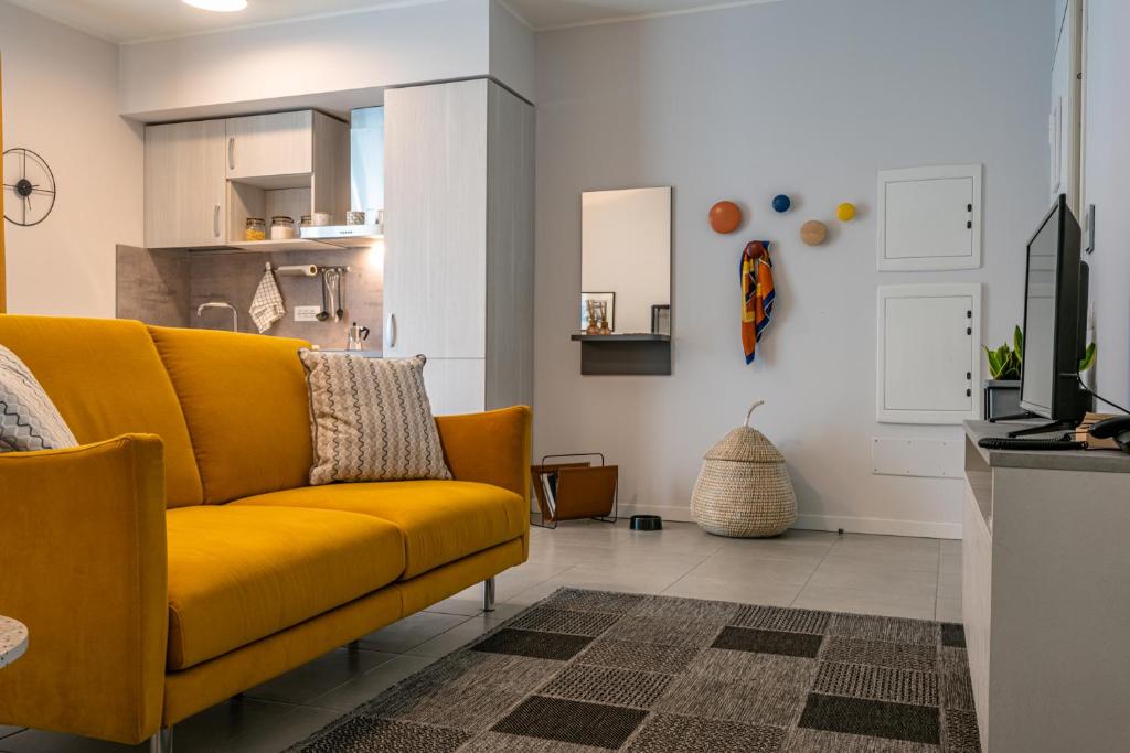 a living room with a yellow couch and a kitchen at Domitys Quarto Verde in Bergamo