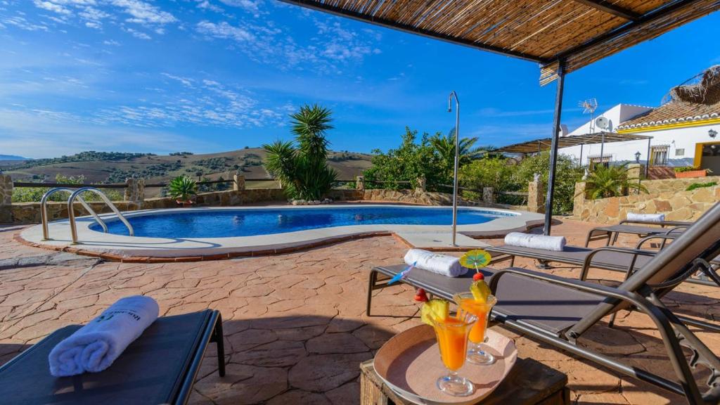 une villa avec une piscine et une table avec une boisson dans l'établissement Casa Hidalgo Villanueva de la Concepcion by Ruralidays, à Villanueva de la Concepción