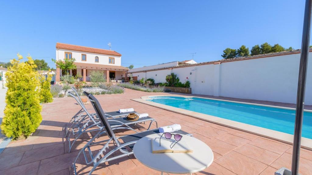 eine Terrasse mit Stühlen und einem Pool in der Unterkunft Casa Embalse Bermejales Arenas del Rey by Ruralidays in Arenas del Rey