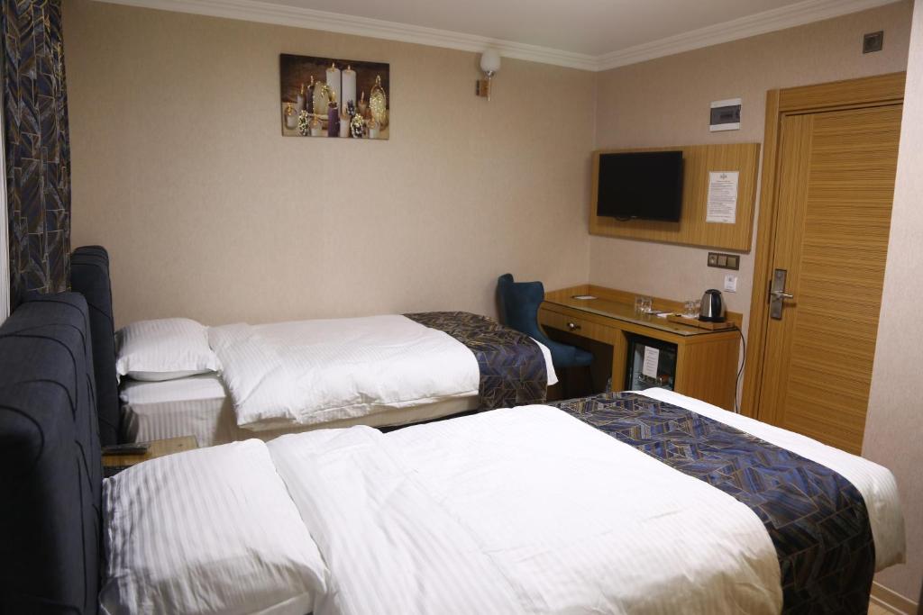 a hotel room with three beds and a television at Hanemir Otel in Tatvan