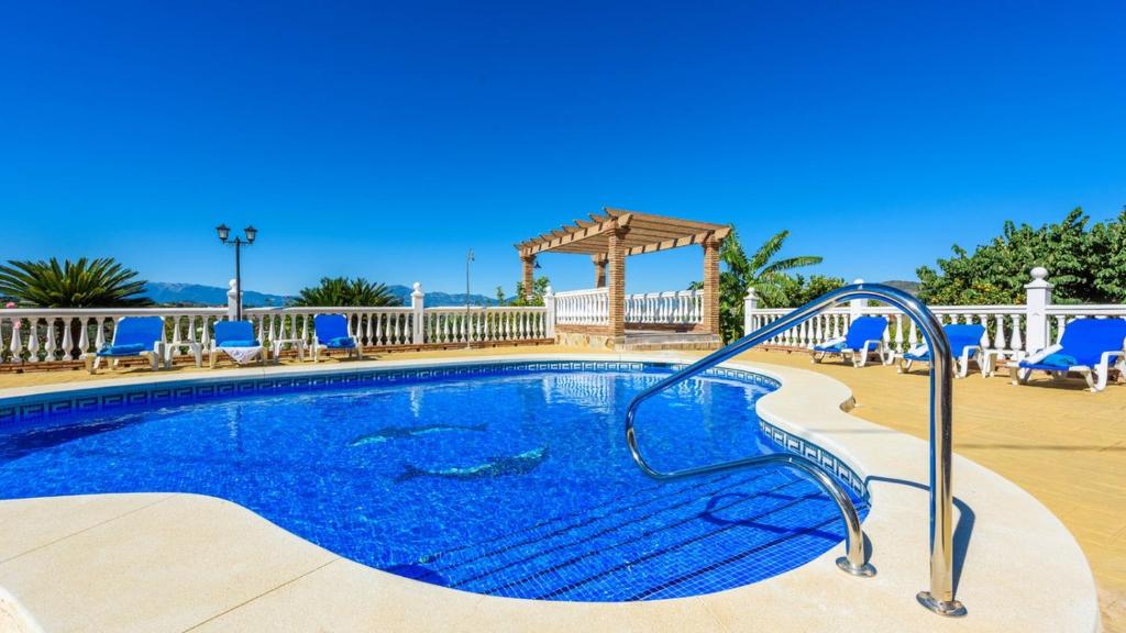 una piscina en un complejo con sillas azules en Villa Galiano Alhaurin de la Torre by Ruralidays, en Alhaurín de la Torre