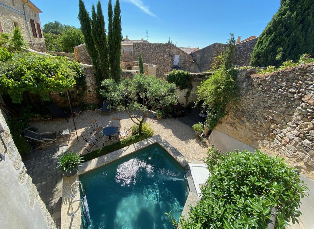 una piscina en un patio con una pared de piedra en La Maison Blanche Uzès, en La Bastide-dʼEngras