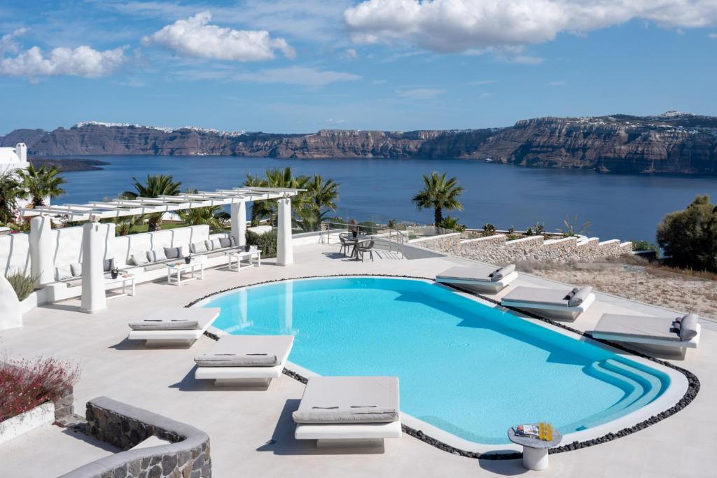 una piscina con sillas y vistas al agua en Elements of Caldera Suites en Akrotiri